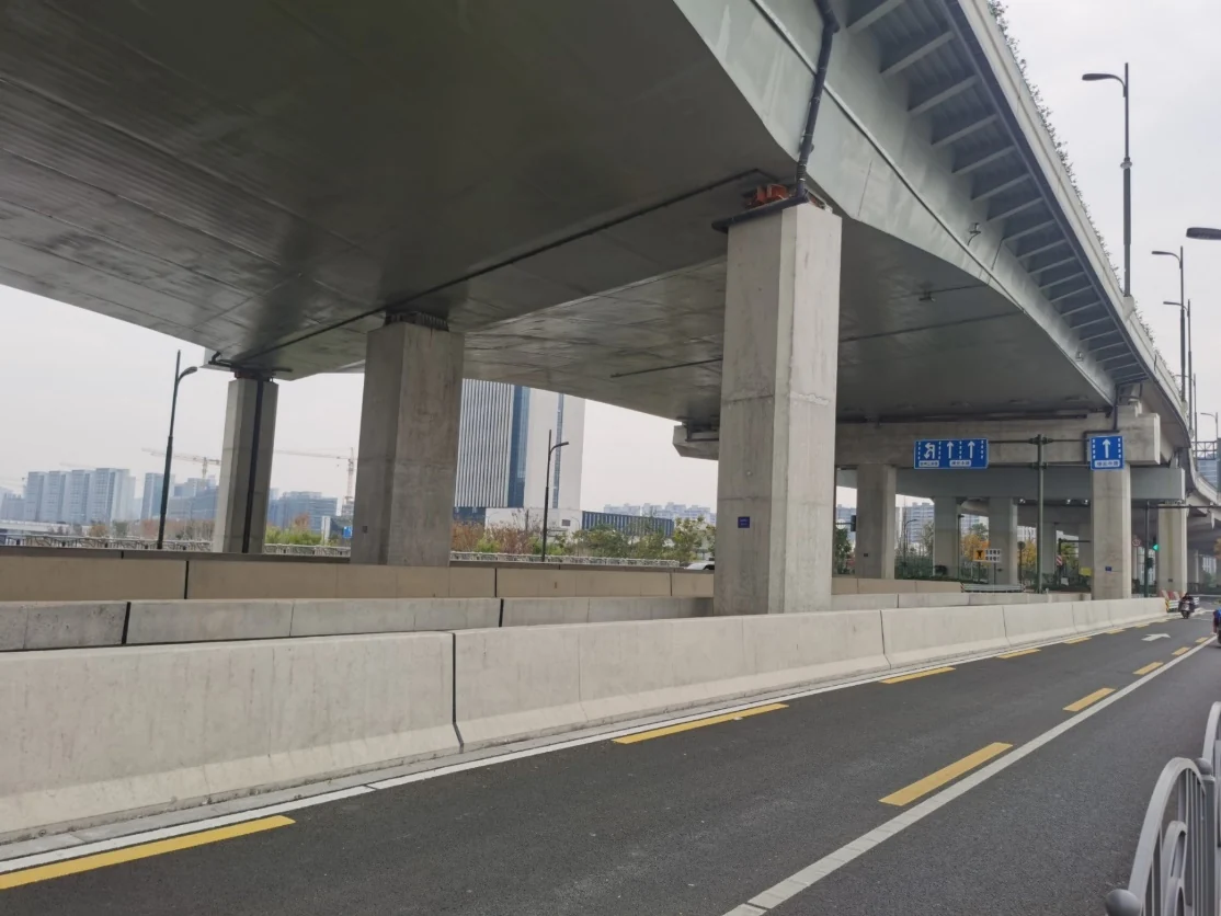 绿云路高架现场照片：桥下道路视角，可见连续钢箱梁、高架桥墩和城市道路